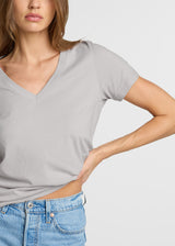 Woman wearing a gray t-shirt and blue jeans on a light gray background. Close up.