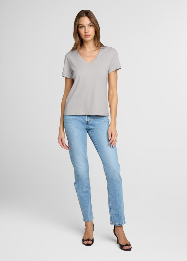 Woman wearing a gray t-shirt and light blue jeans on a white background. Front.