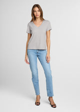 Woman wearing a gray t-shirt and light blue jeans on a white background. Front.