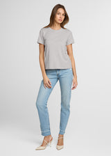 Woman wearing a gray t-shirt and light blue jeans on a white background. Front.
