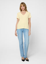 Woman wearing a yellow top and light blue jeans on a white background