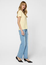 Woman wearing a light yellow top and blue jeans on a white background