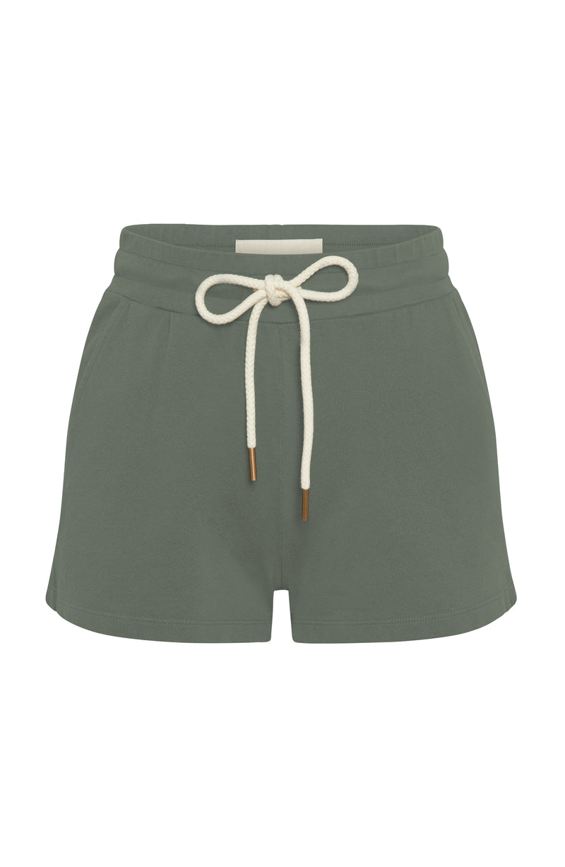 Woman’s relaxed fit jogger shorts made of organic and recycled cotton French Terry with elastic waist, side pockets, and brass capped drawcords in color Thyme Green on Mannequin
