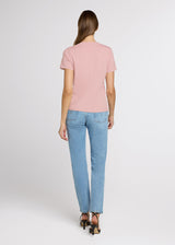 Woman wearing a pink t-shirt and light blue jeans on a white background. Back.