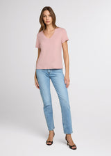 Woman wearing a pink top and light blue jeans on a white background. Front.