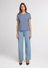 Woman wearing a blue t-shirt and light blue jeans on a white background. Front. 