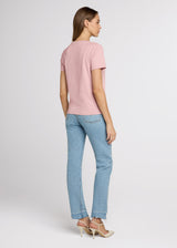Woman wearing a pink t-shirt and light blue jeans on a white background. Back.