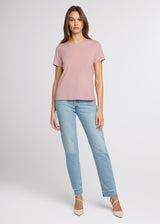 Woman wearing a pink t-shirt and light blue jeans on a white background. Front.