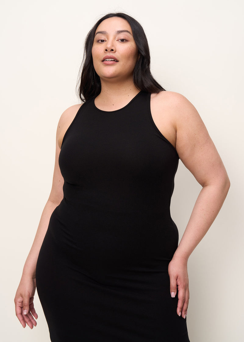 Woman in comfortably form fitted, racerback and crew neck midi dress made of mid-weight and soft Tencel™ Lyocell stretch rib fabric and eco-friendly dyes in color onyx black, close up of neck and arm opening