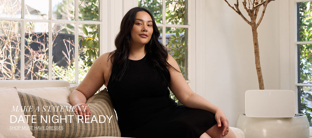 Woman in black dress lounging on couch.