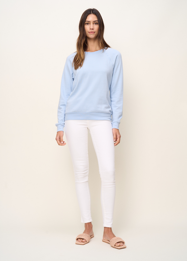 Woman in crewneck raglan sweatshirt made of organic and recycled cotton French Terry in color sky blue, front