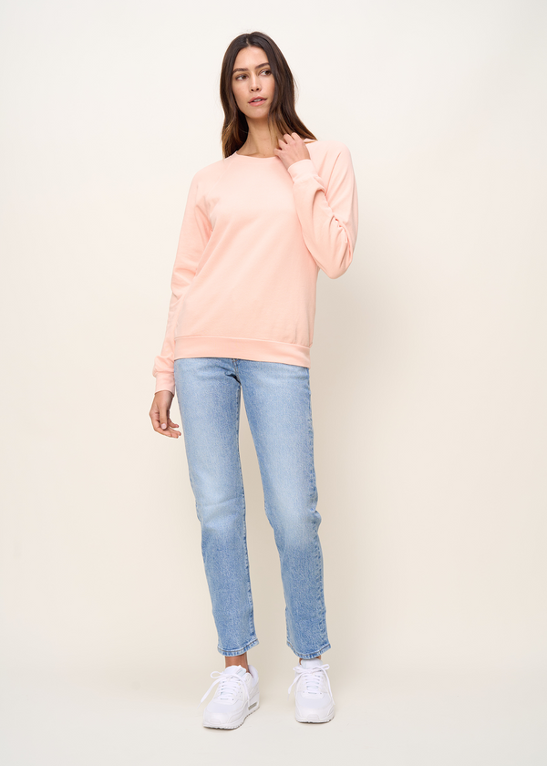 Woman in crewneck raglan sweatshirt made of organic and recycled cotton French Terry in color peach, front