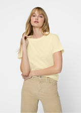 Woman wearing a yellow top and beige pants on a white background. Close up