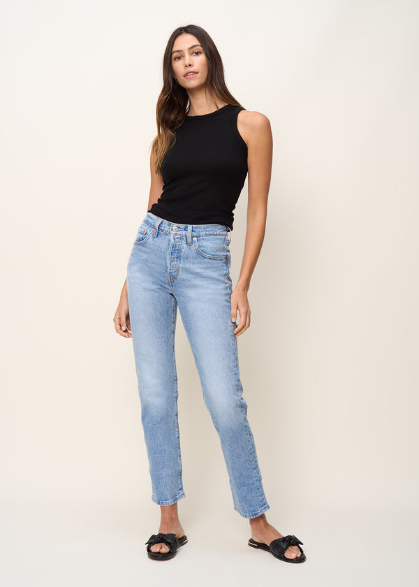 Woman in crewneck tank top made of soft tencel rib knit fabric with racerback detail and binding at neck and armholes in color black onyx paired with denim and black sandals