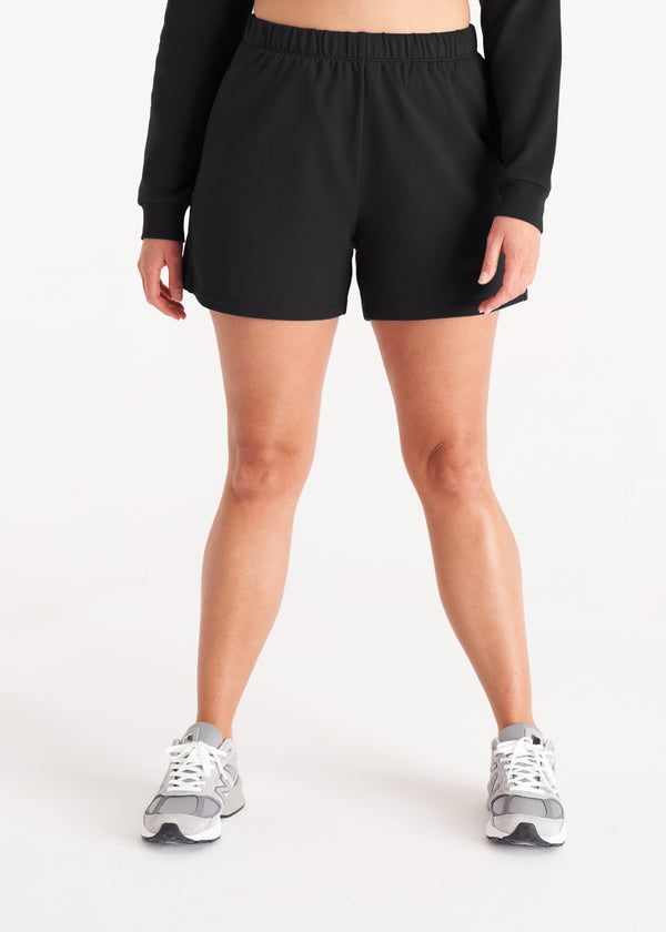 Woman in relaxed fit sweat shorts with elastic waist, side pockets, and interior drawcords made of organic and recycled cotton French Terry in color Onyx Black, Front