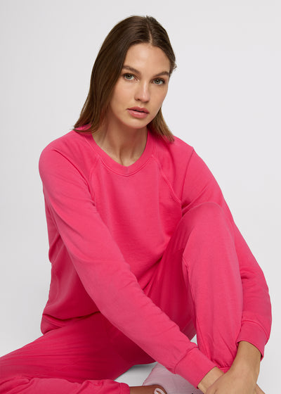Woman in pink sweatshirt and pink sweatpant sitting on the ground.  