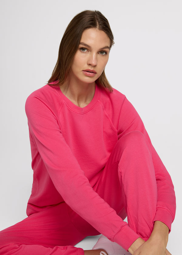Woman in pink sweatshirt and pink sweatpant sitting on the ground.  