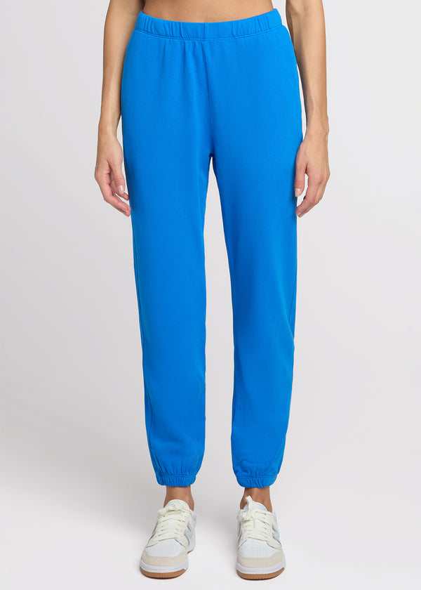 Woman in blue sweatpant standing with her hands at her side. Front. 