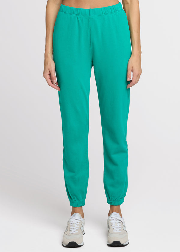 Woman in green sweatpant standing with her hands at her side. Front. 