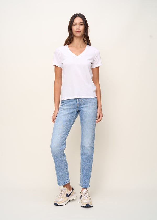 Woman in relaxed fit V neck t-shirt with short sleeves made of organic and recycled cotton jersey and eco-friendly dyes in true white paired with blue jeans