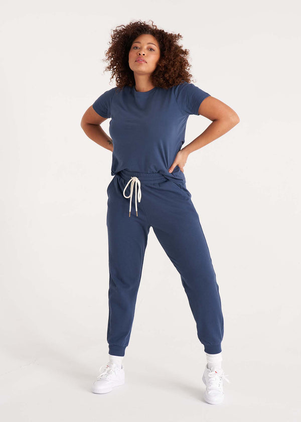 Woman in relaxed fit crew neck t-shirt with short sleeves made of organic and recycled cotton jersey and eco-friendly dyes in midnight navy paired with midnight navy jogger pants