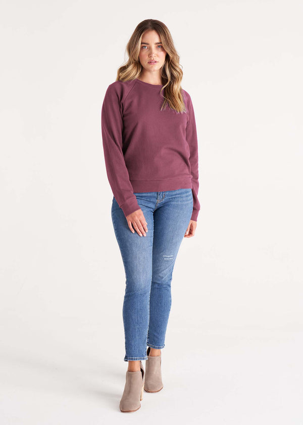 Woman in crewneck raglan sweatshirt made of organic and recycled cotton French Terry in color plum purple, front